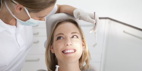 Germany, Young woman getting her teeth examined by dentist