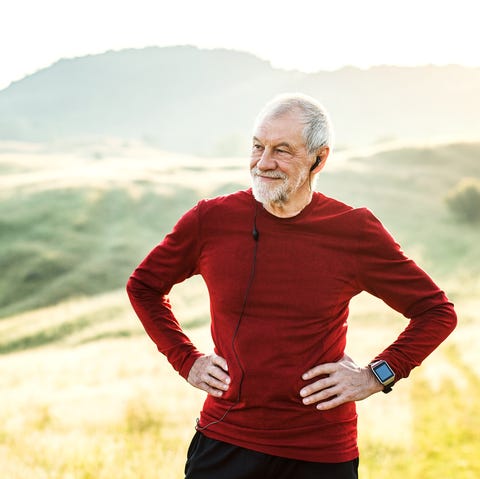 an old male happy sportsperson standing and resting after the run, arms on hips