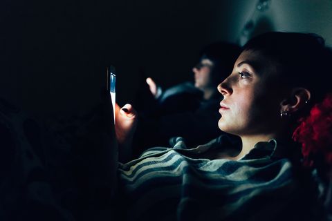 Women in bed in darkness using mobile phones