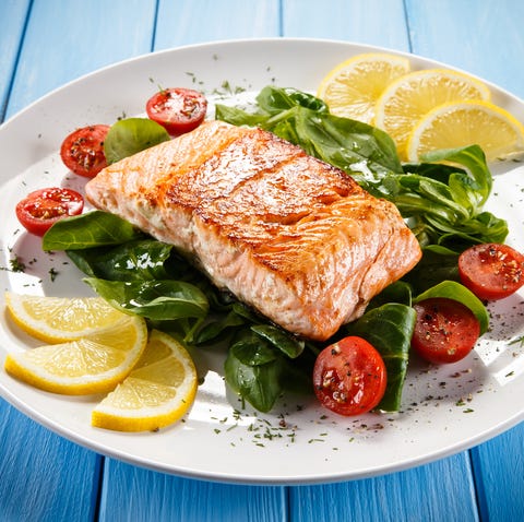 Grilled salmon with French fries and vegetables on wooden table