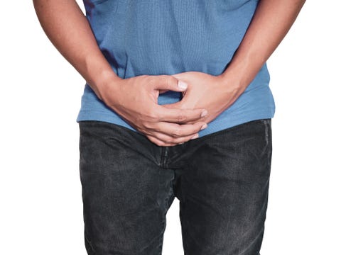 man hands holding on middle crotch of trousers with pain action isolated on white background