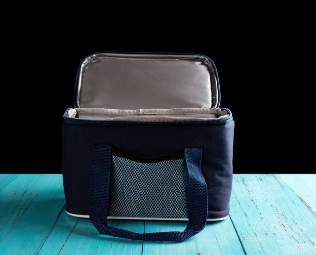 front view grey and blue lunch pack carrier with the top opened on a wood table on black background