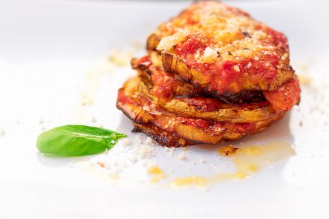 Parmigiana di melanzane. Traditional Italian dish: Baked eggplants with Parmesan cheese, decorated with fresh basil.