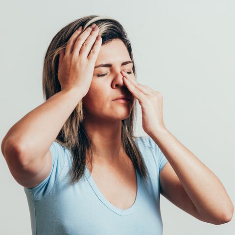 Woman holding her nose and head because sinus pain