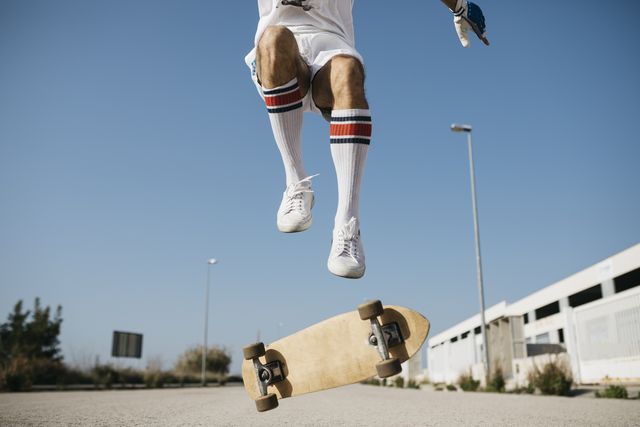 sportive man jumping above ground with skateboard performing trick
