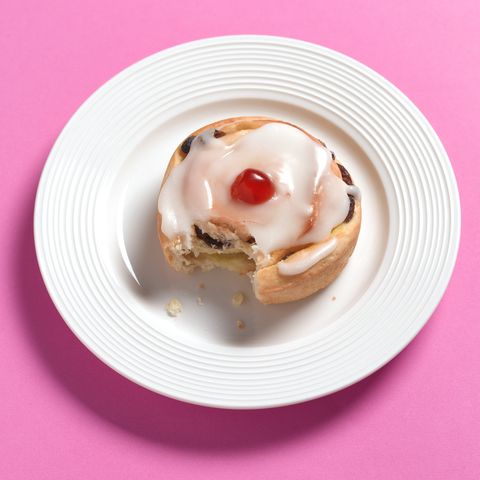 iced Belgian Bun on a plate with a bite taken out of it