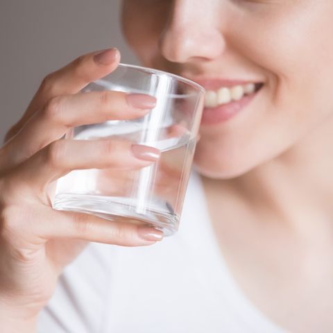 close up of smiling woman feeling thirsty enjoying pure mineral water, dehydrated young female holding glass drinking aqua, girl taking care of own health concept of healthy lifestyle, good habit