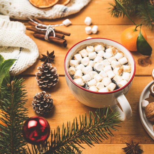 cup of hot chocolate with marshmallows and christmas decorations on wooden table closeup view cozy winter holidays composition