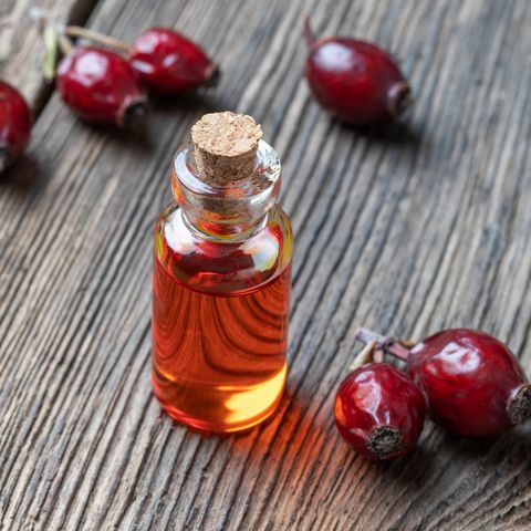A bottle of rose hip seed oil with dried rose hips