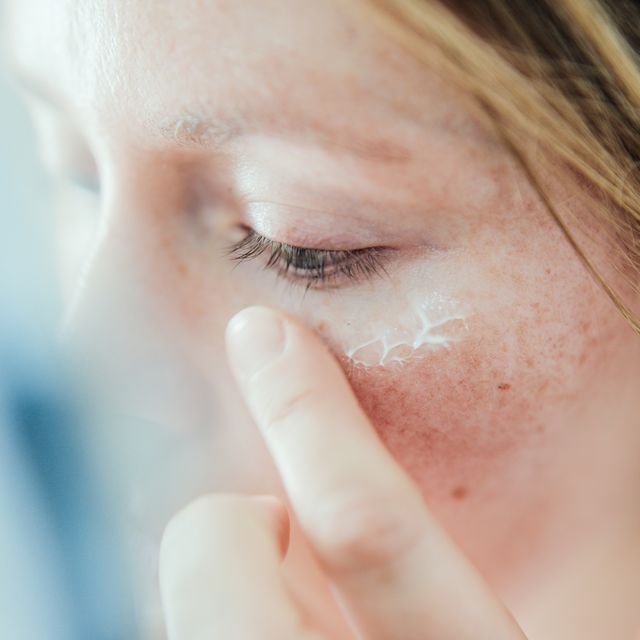 Woman applying skin face cream.