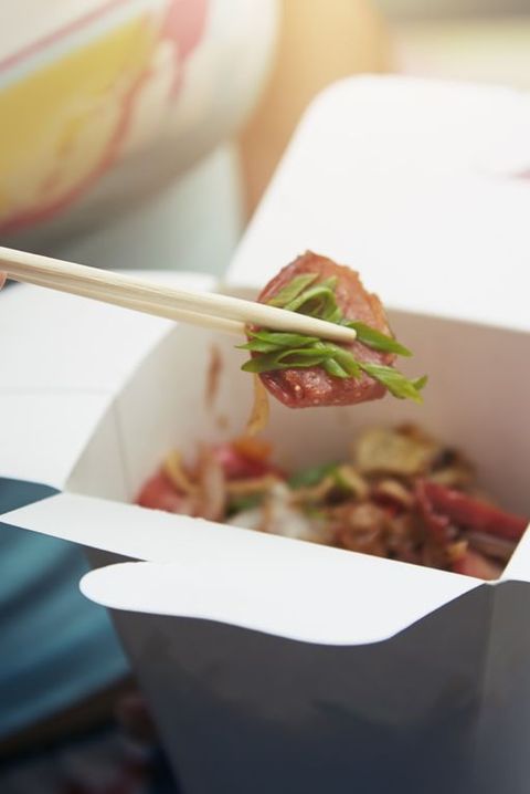 Woman eating Asian fast food from a cardboard box