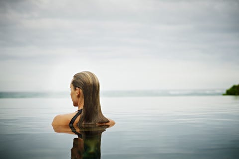 Woman standing in infinity pool overlooking ocean