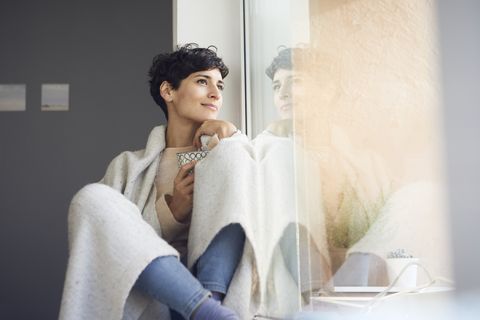 Relaxed woman at home sitting at the window