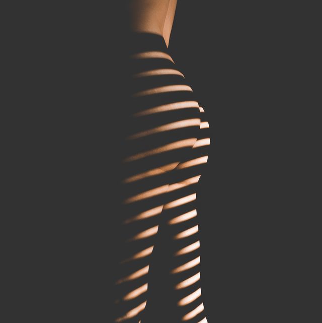 Midsection Of Naked Woman Standing Against Black Background
