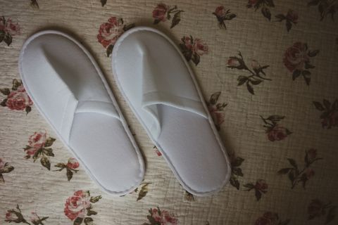 white towelling hotel disposable slippers over old and rust bed sheet old and classic vintage style with noise and grains added