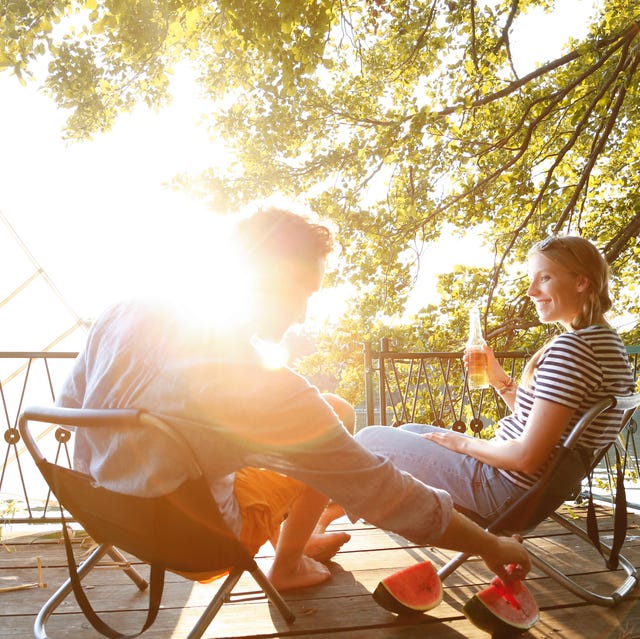 Young couple sitting on a jetty at a lake eating watermelon