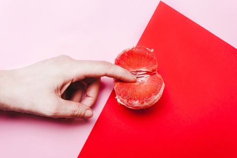 concept sex, masturbation hand, fingers in grapefruit, vagina symbol on a red background