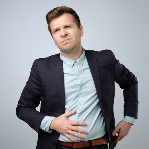 European young man in suit having stomach pain. Colic or flatulence
