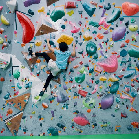A teenage girl climbing a bouldering wall at a sport climbing gym in Japan