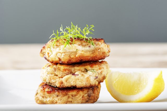 traditional danish fiskefrikadeller or fish cakes fiskefrikadeller are made from finely chopped white fish, usually cod  or haddock, with small pieces of more roughly chopped salmon added, along with cream, onion, carrot and  flour, salt and white pepper served with slices of lemon, parsley and dill colour, horizontal with some copy space