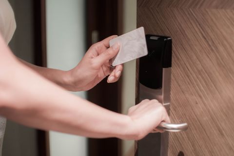 A young woman is opening a door using a card key