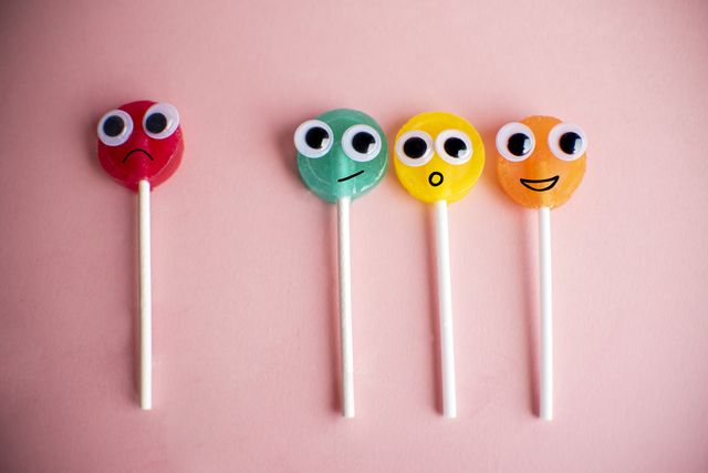 green lollipop with cartoon eyes on pink colored background, bullying concept