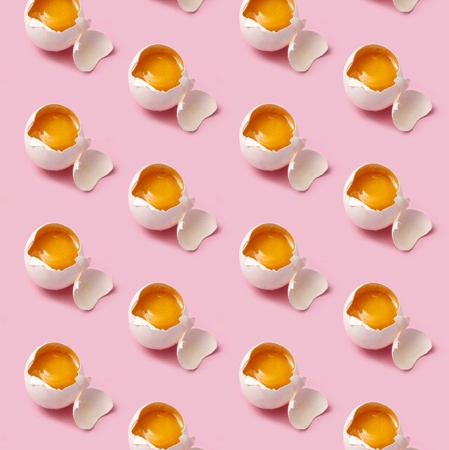 Broken eggs arranged in rows on pink background