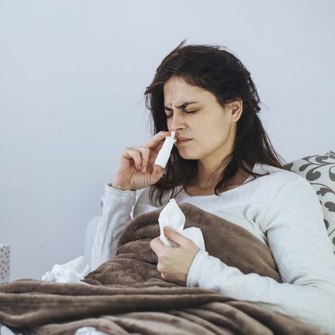 Woman using a nasal spray in bed