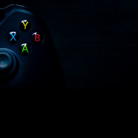 sheffield, uk   june 2nd 2019 shot taken overhead of half a black microsoft xbox one controller with emphasis on the colourful buttons sitting on the left of a dark black background, perfect for presentation material like powerpoints