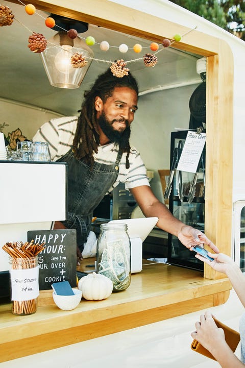 Smiling food truck owner taking credit card for payment from customer Smiling food truck owner taking credit card for payment from customer