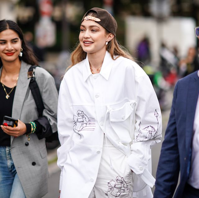 paris, france   june 20 gigi hadid wears a brown cap, earrings, necklaces, a white shirt with cartoon drawings pattern, assorted  pants,  outside vuitton, during paris fashion week   menswear springsummer 2020, on june 20, 2019 in paris, france photo by edward berthelotgetty images