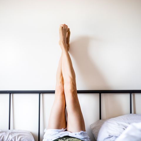 Woman with Legs Raised wearing white shorts lying on bed