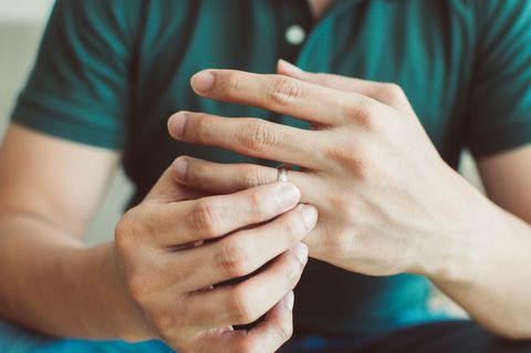 a mid section of a young man wearing a green shirt is holding his wedding ring