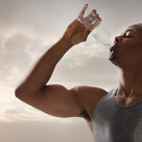 USA, Utah, Salt Lake City, Athlete young man drinking water form bottle, cloudy sky in background this guy is just going to town on water drinking