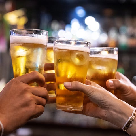 group of happy friends drinking and toasting beer at brewery bar restaurant   friendship concept with young people having fun together at cool vintage pub   focus on middle pint glass   high iso image