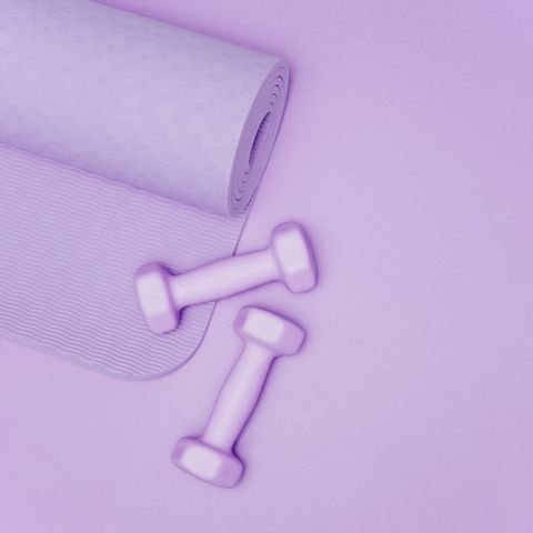 yoga mat and dumbbells on purple background