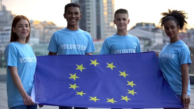 young multi racial volunteers holding european union flag, international unity