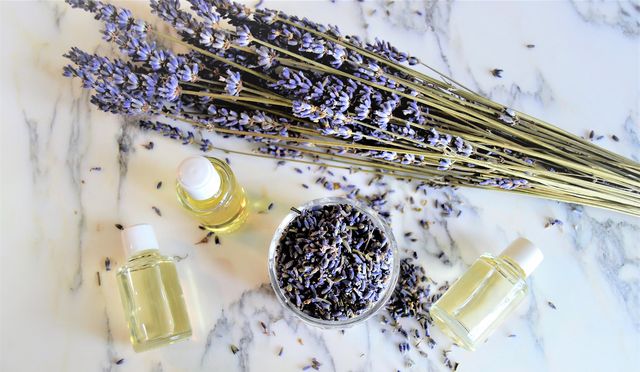 aromatic oils with lavender flowers on marble background, seen from above