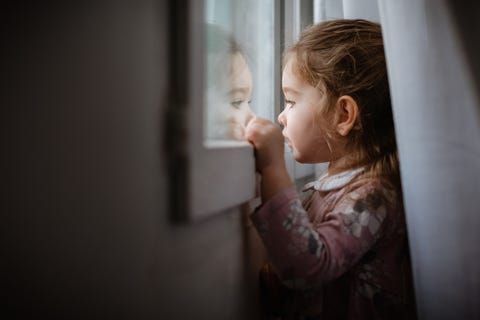 Side view of young girl looking outside window at rain Side view of young girl looking outside window at rain