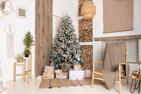 decorated christmas living room interior with beautiful fir tree gift boxes on the floor, firewood for a fireplace