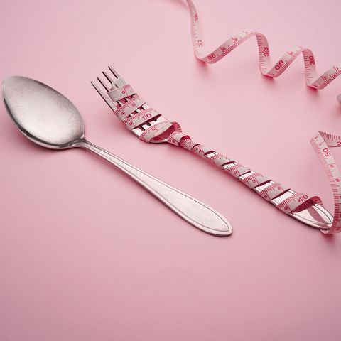 High Angle View Of Tape Measure With Spoon And Fork On Pink Background