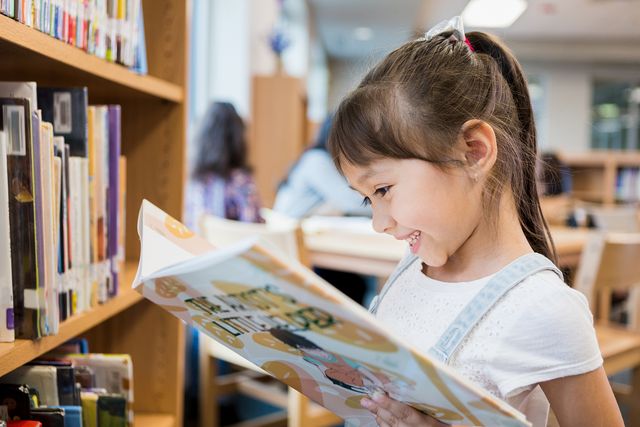 una niña feliz lee en una biblioteca