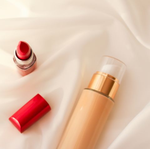 High Angle View Of Lipstick And Liquid Foundation Bottle On Satin