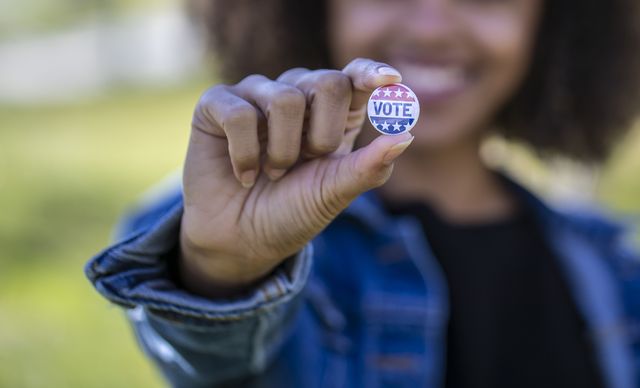 a young african american woman holding a voting badge