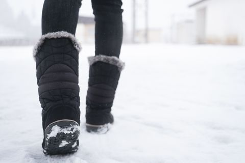 legs of woman walking in winter park evening girl boots walking snow weather closeup of winter shoes