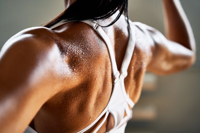 close up of woman back with flexing her muscles in sweat on skin after workout female bodybuilder with perfect biceps