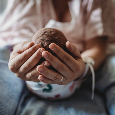 Macro view of mothers hands holding newborn boy's head