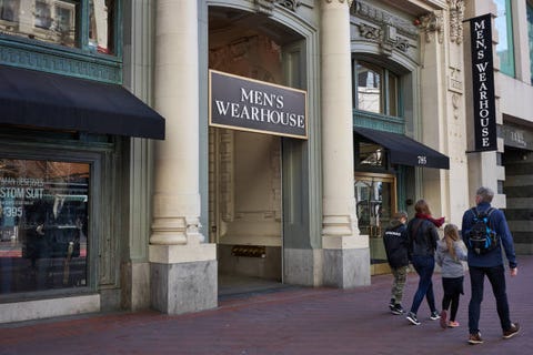 san francisco, ca, usa   feb 9, 2020 a family of four walking past the mens wearhouse store on market street in the soma district in san francisco, california