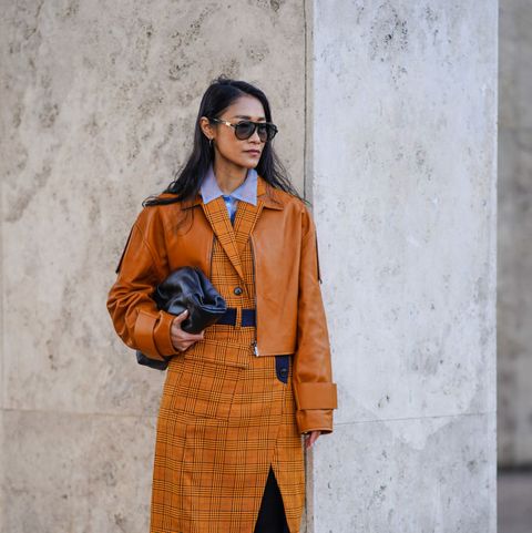paris, france   february 29 fashion blogger pornwika wears sunglasses, a mauve shirt, an orangebrown leather jacket, a checked dress, cow pattern printed white and brown high boots, a black leather bottega veneta bag, outside rokh, during paris fashion week   womenswear fallwinter 20202021, on february 29, 2020 in paris, france photo by edward berthelotgetty images
