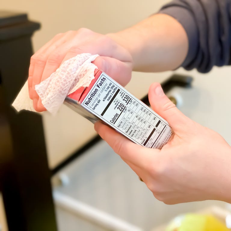 father uses anti-bacterial wipe to sanitize groceries delivered by a grocery delivery service